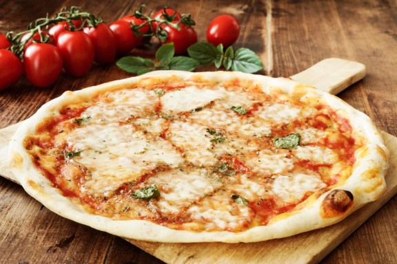 Neapolitan Style Pizza on a wooden board - with buffalo mozzarella, tomato sauce and fresh basil