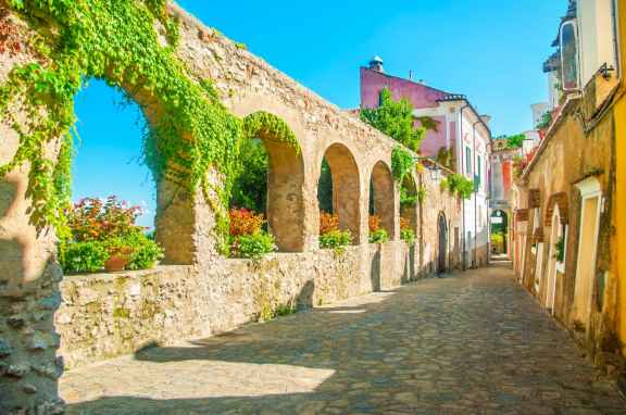 Old stone streep with stone arches and crooked houses in bright colours, in Ravello on the Amalfi Coast of Italy
